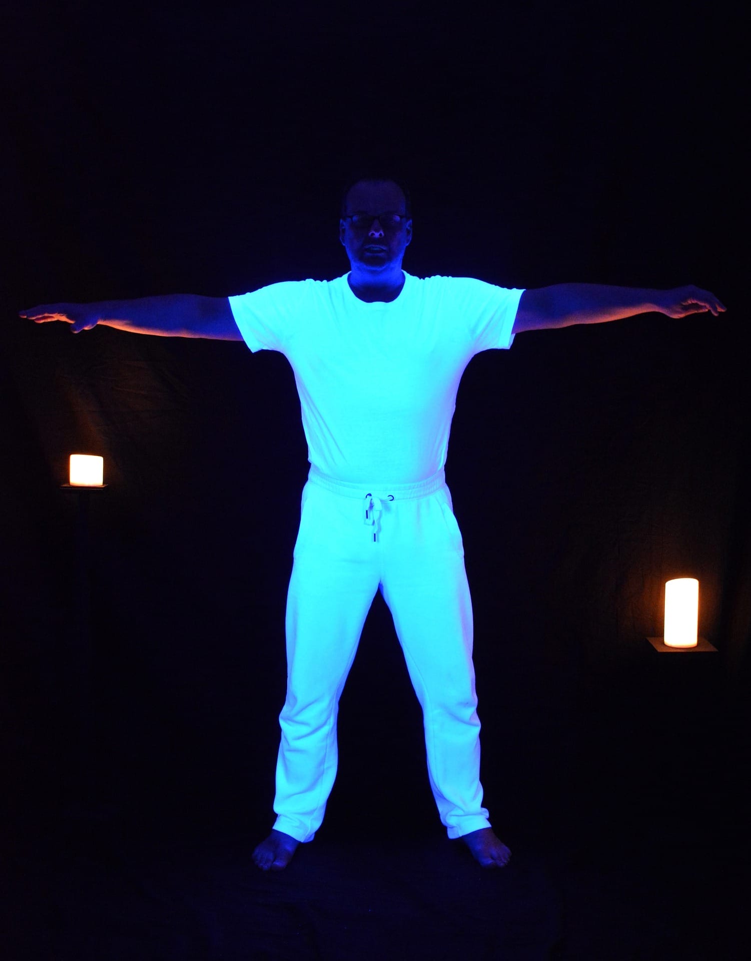 A man standing arm spread exposed to 365nm UV light